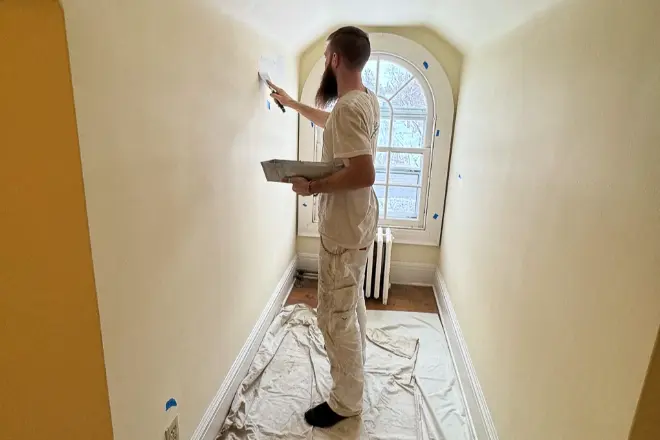 Professional painter applying fresh paint to a bright interior wall